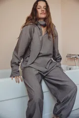 Camisa de algodón con diseño a rayas verticales, escote en pico con detalle de pañuelo ajustable mediante lazada, manga larga con puños abotonados y aberturas laterales en el bajo.