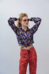 Pantalón de vestir de tiro alto, color rojo con estampado de flores grandes en tono marrón oscuro. Diseño recto con cordones ajustables en la cintura.