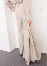 Pantalón de vestir de tiro medio, color beige, de corte recto y amplio con pinzas frontales.