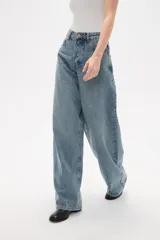 Pantalon de jean azul de corte ancho y tiro medio, con diseño de cinco bolsillos y cierre frontal con botón y cremallera.