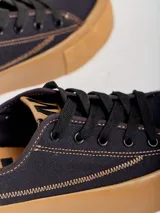 Championes de lona negra con plataforma y puntera de goma marrón, cordones negros y costuras en contraste.