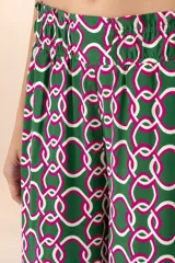 Pantalón largo de corte palazzo, con cintura elástica y estampado de cadenas entrelazadas en tonos verde oscuro, blanco y fucsia.