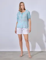 Blusa celeste con estampado floral, cuello redondo con lazo y mangas cortas con volados.