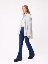 Camisa de corte oversize con diseño a rayas verticales en tonos azul y blanco. Presenta cuello clásico, cierre frontal con botones y un bolsillo en el pecho con detalle de etiqueta.