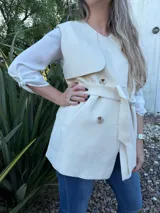 Chaleco color beige con cuello solapa, doble botonadura y lazo para atar en la cintura.