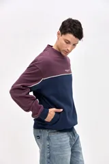 Buzo de cuello redondo en felpa con friza, de calce relajado. Presenta un diseño de bloques de color en azul marino y bordó, con detalles de vivos en color blanco que recorren el cuerpo y las mangas. Incluye un pequeño estampado con el logo de la marca en el pecho.