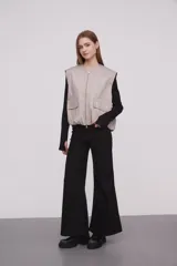 Chaleco color caqui con cierre frontal con cremallera, bolsillos con solapa y corte holgado.