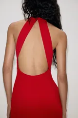 Vestido largo de corte fluido con cuello halter y espalda descubierta. Presenta un detalle de drapeado lateral y bajo recto.