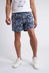 Short de baño con cintura elástica y cordón ajustable, confeccionado en tela ligera de secado rápido. Presenta un estampado botánico integral en tonos amarillos, blancos y azules, con dos bolsillos delanteros y uno posterior.