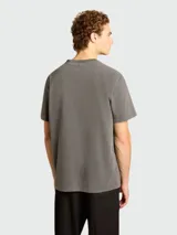 Remera gris de algodón con efecto desgastado, cuello redondo y estampado con la palabra 'GOLDEN' invertida en el frente.