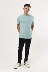 Remera de algodón color celeste claro, manga corta y cuello redondo, con un pequeño texto estampado en negro en la zona del pecho.