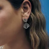 Aros colgantes plateados con forma de concha marina con diseño calado. Los pasadores son de acero quirúrgico hipoalergénico.