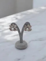 Caravanas de diseño floral con forma de hoja metálica plateada y perla central.