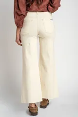 Pantalón de jean color beige, de corte wide leg con botamanga desflecada y tiro medio, diseñado especialmente para maternidad.