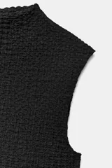 Top negro de cuello perkins y sin mangas, confeccionado en tejido texturizado con ajuste al cuerpo.