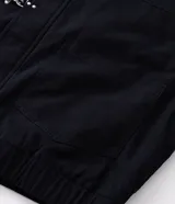 Campera de sarga de algodón con capucha, cierre frontal con cremallera y trabas metálicas decorativas. Presenta un bolsillo con cierre en la manga y puños elásticos, con un diseño de estilo utilitario.
