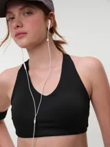 Top deportivo negro con espalda nadadora, copas removibles y detalle de logo sutil en el elástico inferior.