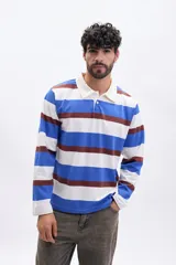 Remera de manga larga tipo polo con cuello camisero y cierre frontal de botones. Presenta un diseño de rayas horizontales anchas en tonos azul, blanco y marrón.