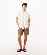Bermuda de sarga negra de corte recto y holgado para hombre, con bolsillos cargo laterales con solapa, cintura con pasadores y cierre frontal con botón y cremallera.