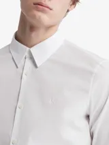 Camisa blanca de vestir, corte slim fit, con cuello clásico, cierre con botones y logo bordado en el pecho.