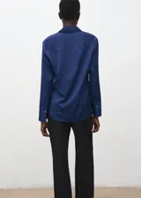 Camisa de satén azul satinado con cuello camisero, manga larga y cierre frontal de botones.