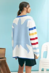Cardigan de punto con cuello redondo, botones frontales y diseño de rayas horizontales en tonos blanco, celeste, azul, amarillo y rojo. Presenta puños y ruedo en azul.