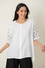 Blusa negra de viscosa con estampado de flores blancas en las mangas, corte holgado, cuello redondo y botones frontales.