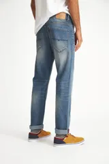 Jean de calce recto, color azul medio, con terminación arremangada.