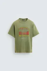 Camiseta de punto de algodón con corte relaxed fit, cuello redondo y manga corta. Color verde oliva con efecto lavado y estampado frontal con diseño gráfico en tonos rojo y amarillo.
