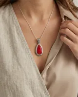 Dije de plata 925 con diseño de filigrana en forma de lágrima, engastado con una piedra natural de coral rojo. Incluye cadena de plata fina.
