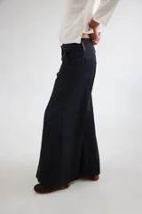 Pantalón de tiro medio-alto con piernas anchas y corte recto. Presenta cierre frontal con botón, bolsillos laterales y detalles de costuras verticales. Confeccionado en tencel.