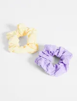 Set de dos gomitas para el pelo tipo scrunchie, una color amarillo pastel y otra color lila, ambas con estampado de flores pequeñas y lentejuelas.
