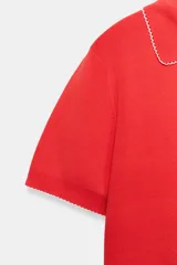 Top de punto color crudo, con cuello polo y escote en V. Cuenta con mangas cortas y detalle de puntilla con forma de onda en el cuello y los puños.