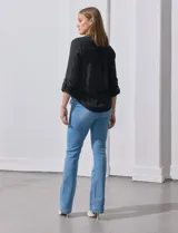 Blusa blanca de gasa marca Zac & Rachel, con cuello a la base, escote en V, abertura central con botones, bolsillo aplicado en el pecho y mangas largas regulables con presilla y botón. Tiene terminación opcional de nudo en el ruedo.