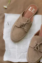 Mules de gamuza color tostado con diseño de zapato náutico, con cordones frontales y plantilla con logo estampado.