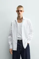 Camisa de corte slim fit confeccionada en tejido de algodón, con cuello italiano, manga larga con puños abotonados y cierre frontal de botones.