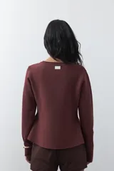 Cardigan negro de tejido de punto con cuello redondo y cierre frontal con botones a contraste. Presenta un corte entallado en la cintura con una silueta levemente evasé y mangas largas.
