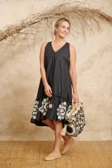 Vestido negro con escote en V, corte holgado, largo midi y volado bordado en el ruedo.