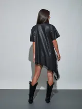 Vestido corto de efecto cuero color negro, de corte recto y holgado, con mangas corta y detalle de encaje negro en el dobladillo asimétrico.