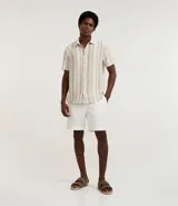 Camisa de hombre de manga corta con cuello tradicional y abotonado frontal. Presenta un tejido texturizado con un patrón de rayas verticales en tonos beige, blanco y marrón claro.