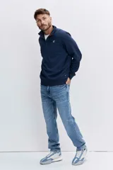 Pantalón de jean corte regular, color azul medio con efecto lavado, de tiro medio y cierre frontal con botón y cremallera.