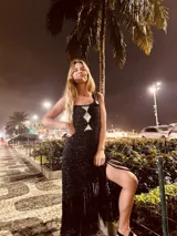 Vestido tejido en lurex color plateado, con diseño geométrico en cuero en el frente y flecos en el ruedo. Breteles finos de cuero con tientos plateados.