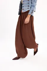 Pantalón marrón fluido de corte ancho y relajado, con cintura elástica fruncida y diseño abombado en las piernas.