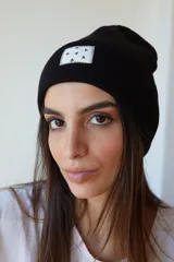 Gorro de lana color lila con etiqueta cuadrada blanca con diseño de triángulos negros.