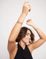 Pulsera doble abierta de metal dorado con un topacio blanco en cada extremo.