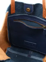 Cartera tipo tote bag de cuero, con diseño bicolor en azul marino y tostado, asas largas para el hombro y costuras reforzadas.