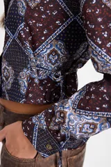 Camisa corta estilo corset de color blanco, con cuello clásico, cierre frontal de botones y detalles de cordones laterales ajustables. Presenta pinzas frontales y traseras para un ajuste entallado.