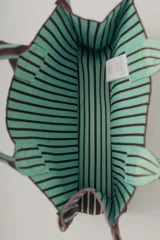 Bolso tote marrón con rayas verticales verde agua. Tiene doble asa corta marrón con rayas verde agua y etiqueta cuadrada con el nombre de la marca en el frente.