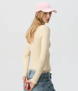 Cardigan de tricot acanalado color beige, de calce ajustado, con mangas largas y escote en V. Cuenta con cierre frontal con botones y detalles de encaje aplicado en el escote y el ruedo.