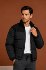 Campera puffer negra con cuello alto, cierre frontal y puños elásticos acanalados.
